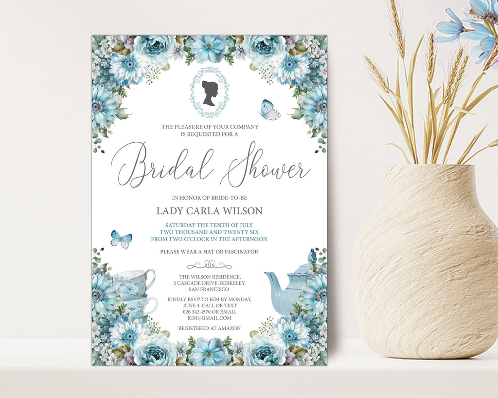 a 5 x 7 blue flower bridal shower invitation with victorian cameo, leaning up against a beige wall next to a vase full of dried blue flowers