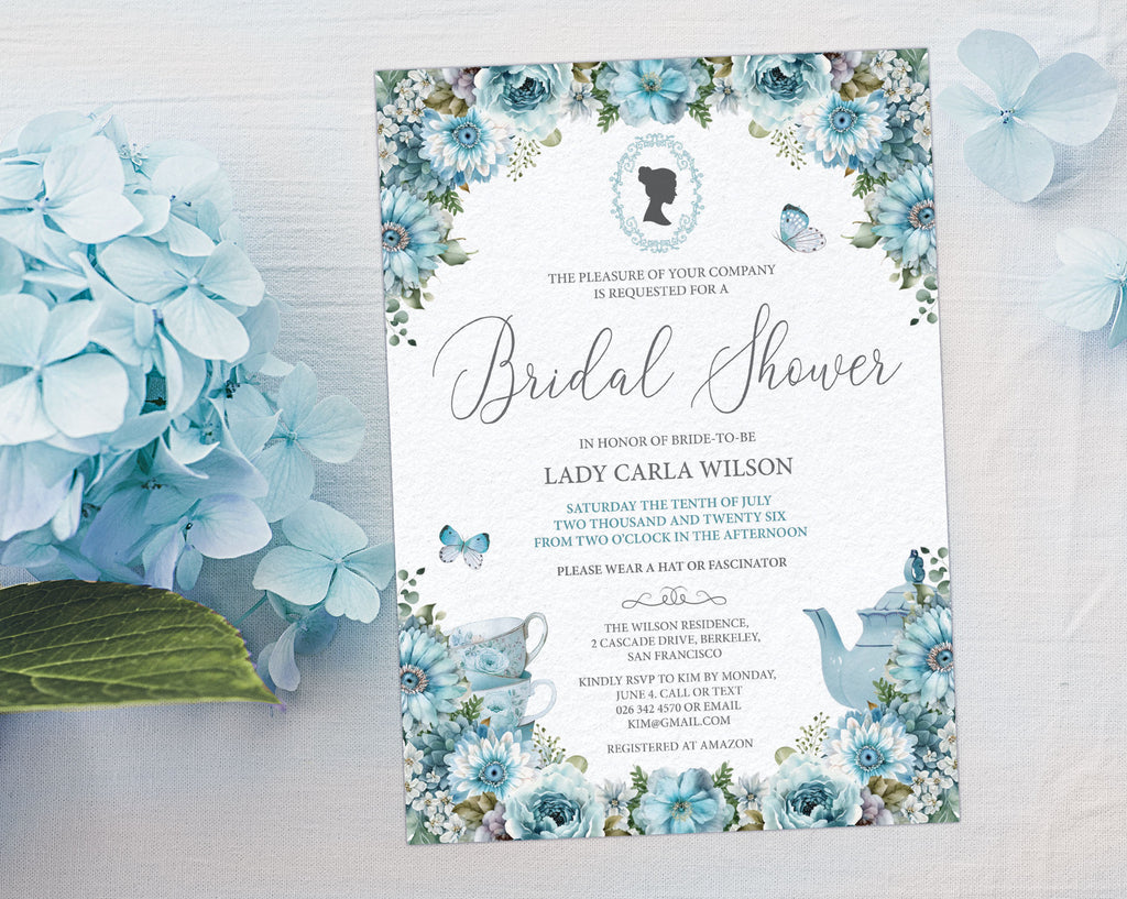 lovely dusty blue 5 x 7 regency style bridal shower invite laying on a grey background next to some blue hydrangeas