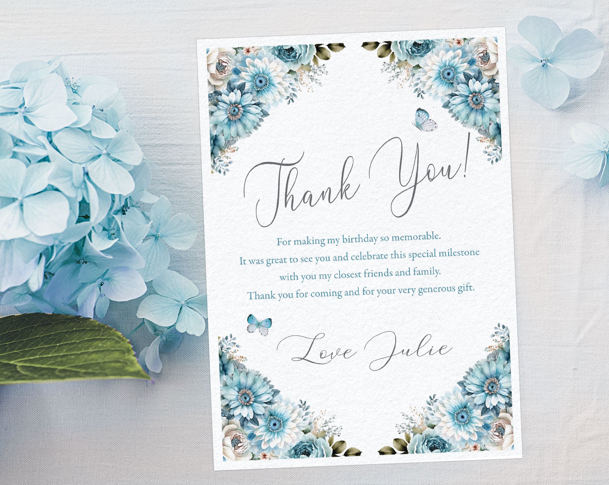 pretty blue flower thank you note laying on a white textured background next to a blue hydrangea