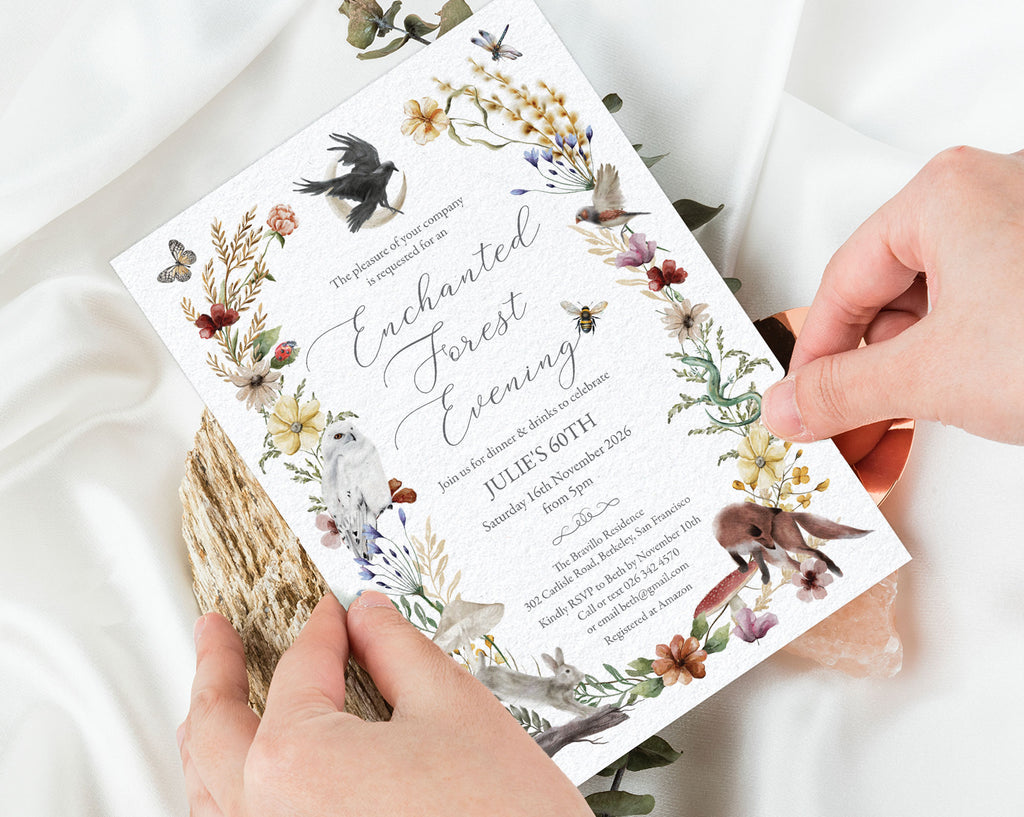 two hands holding a pretty enchanted forest evening dinner invitation with white cloth in the background