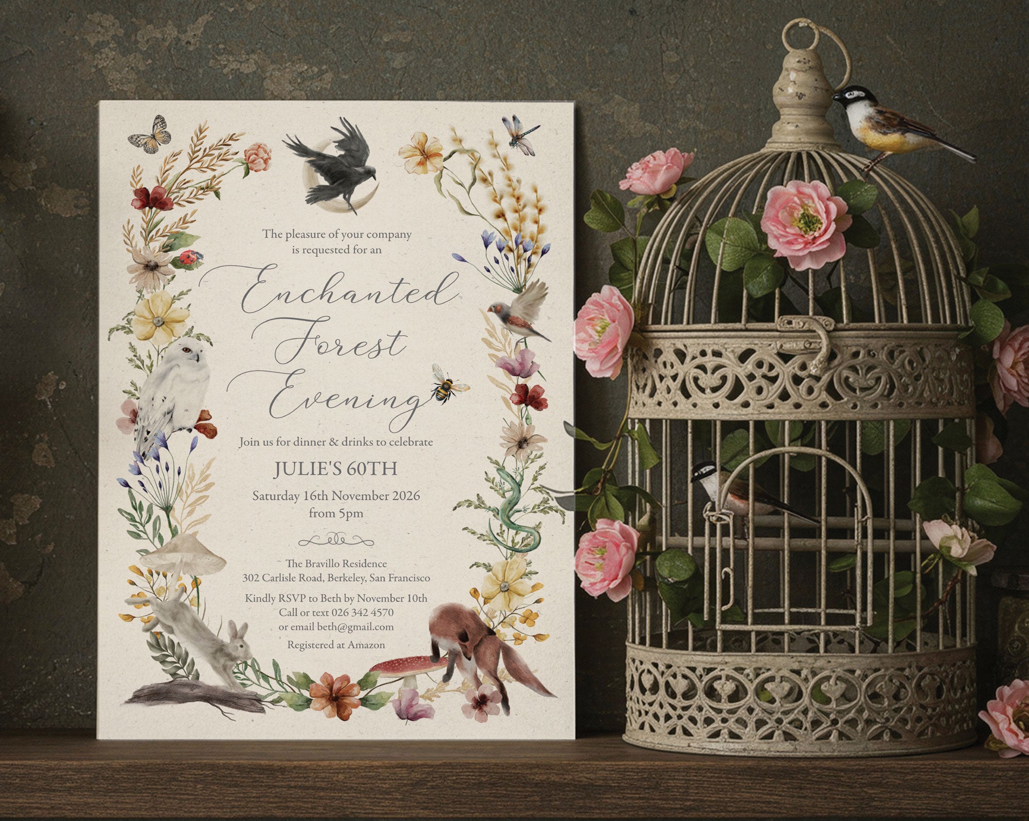 an elegant enchanted forest evening invitation with woodland animals and flora and fauna leaning up against a dark wall next to an ornamental birdcage filled with flowers and toy birds