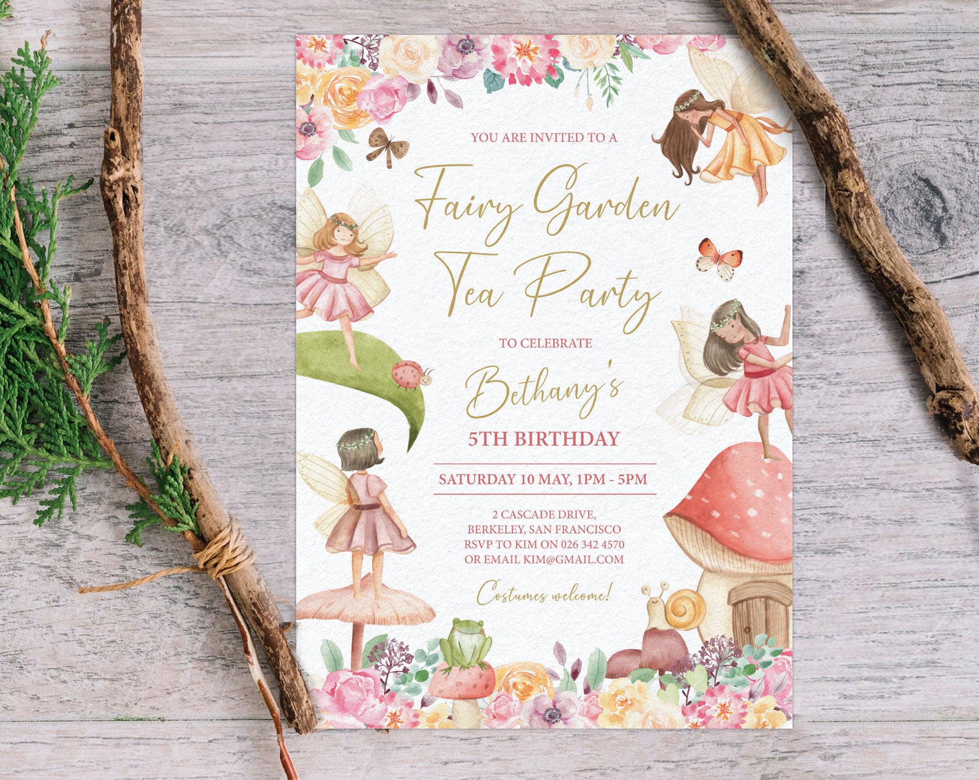 pretty fairy garden tea party invitation lying on a grey wooden surface next to two tree branches