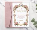 Pretty thank you note with pastel peonies, gold freame, cameo graphics laying on a blush pink envelope on a marble surface