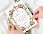 2 hands holding an elegant royal thank you note, with peonies, gold frame and cameo graphics with white silk in the background