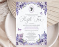 pretty lavender colored flower high tea invitation laying on a white plate with a dried leaf in the background