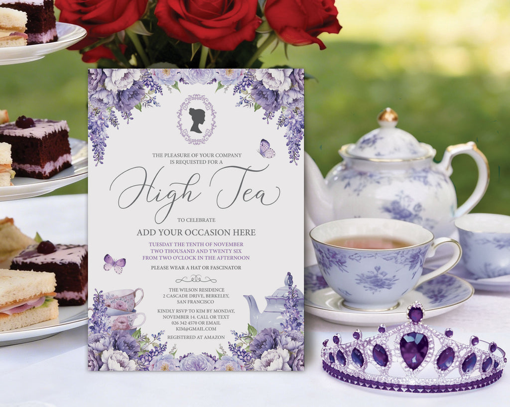 a lavender colored high tea invitation with lilac wisteria flowers and cameo, leaning up against a tiered stand of tea party food on a pretty tea table with purple pattern tea set and red roses