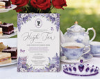 a lavender colored high tea invitation with lilac wisteria flowers and cameo, leaning up against a tiered stand of tea party food on a pretty tea table with purple pattern tea set and red roses