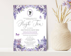 a pretty lavender colored tea party invitation leaning up against a beige wall next to a vase of dried flowers