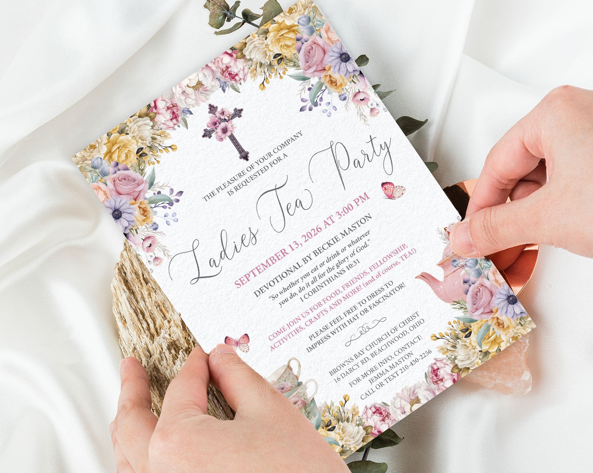 two hands holding a 5 x 7 church ladies tea party invitation in pastel design, over a white background
