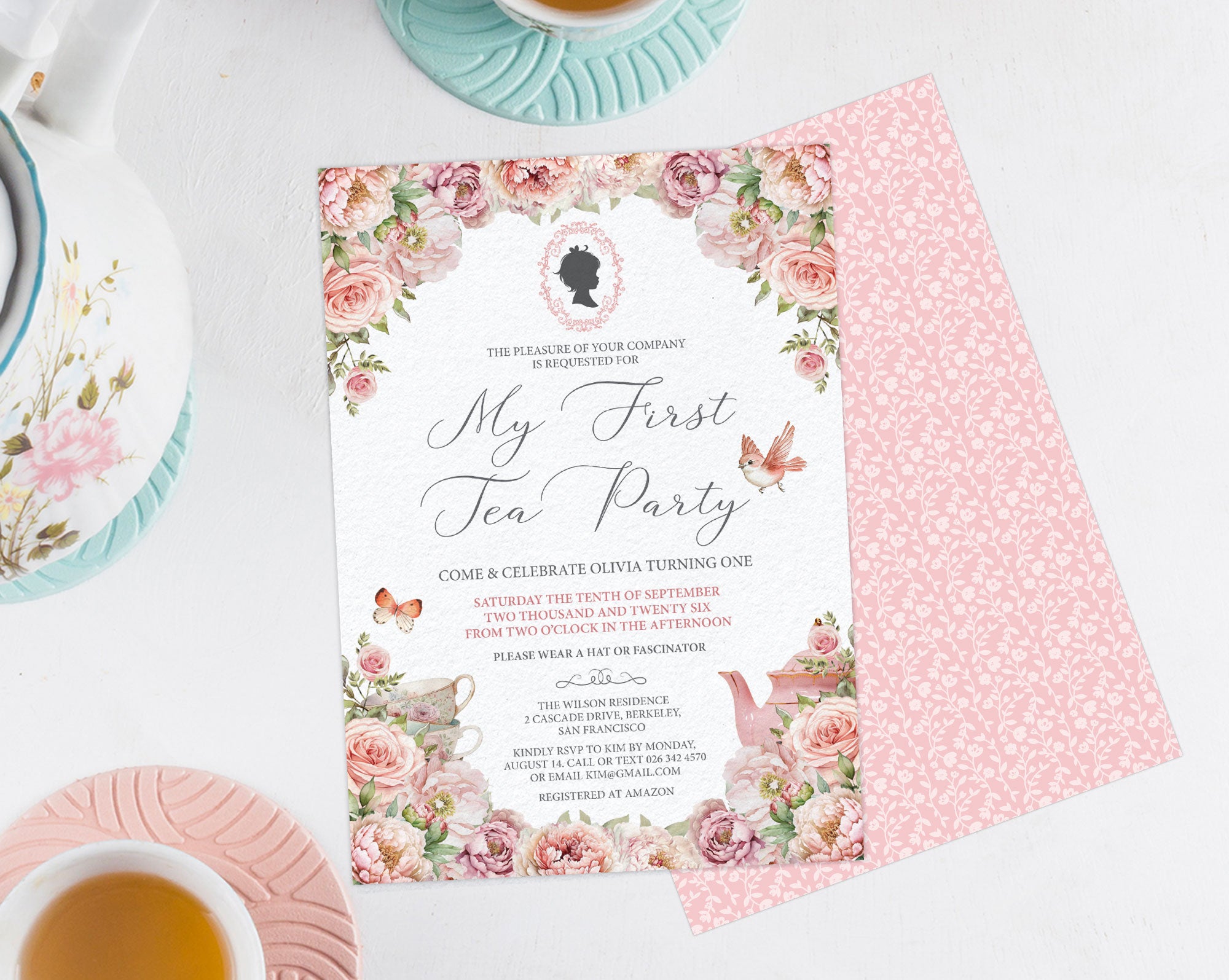 blush pink Invitation card for babys First Tea Party' with floral design on a white surface.