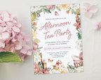 a 5 x 7 afternoon tea invitation laying on a grey background next to a pink hydrangea flower