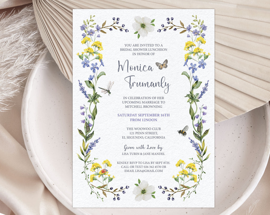 A bridal shower luncheon invitation with wildflowers and butterfly laying on a white plate with a dried leaf in the background