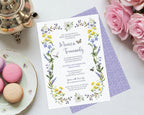 pretty bridal shower invitation with a purple pattern back laying on a light grey background next to some pink roses, macarons and a silver teapot
