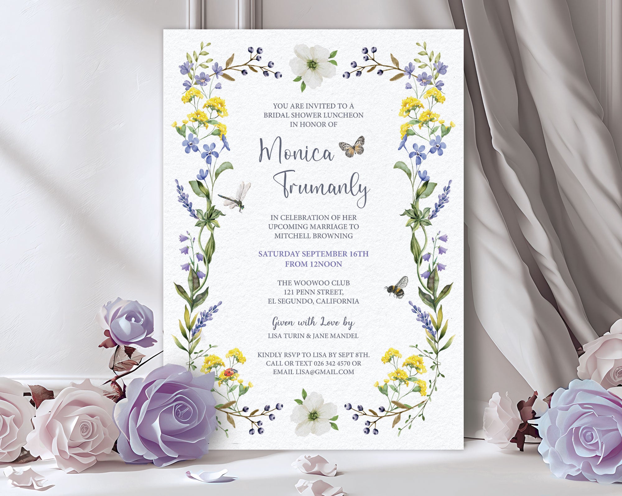 a bridal shower luncheon invitation leaning up against a grey curtain with purple and white roses next to it