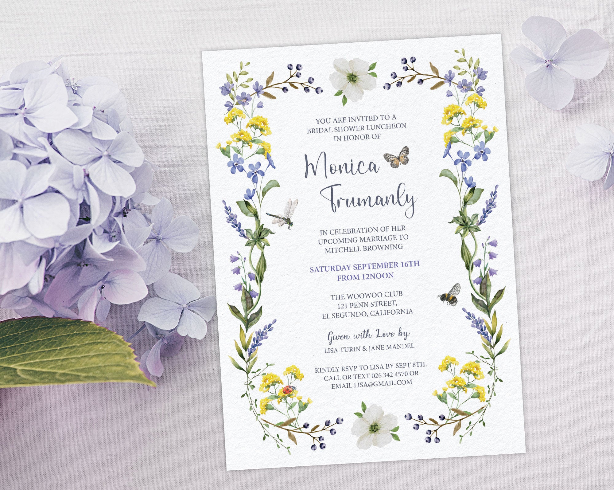 an elegant bridal shower luncheon invitation with wildflowers, butterfly, bee and dragonfly laying on a light grey background next to a lilac hydrangea flower
