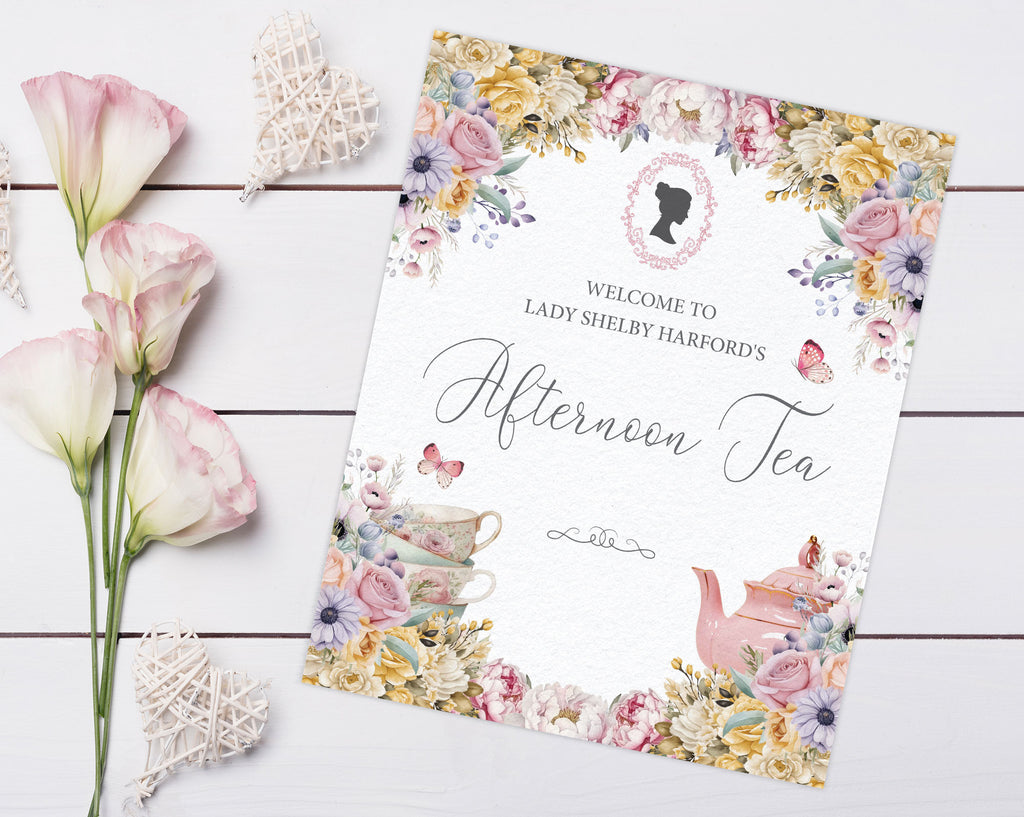 welcome sign with Pastel flowers and Regency cameo, teapot, tea cups and butterflies laying on a wooden background next to some lilies