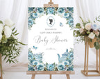 elegant A1 baby shower welcome sign on a wooden easel with white curtains and flowers on stands in the background