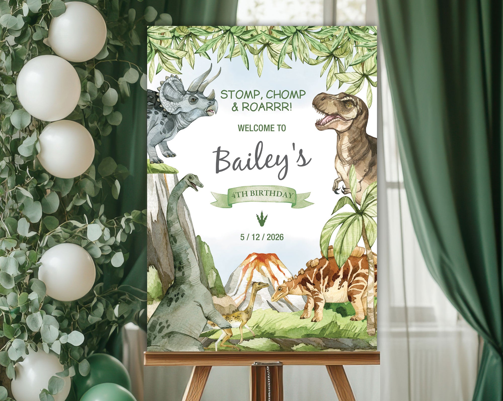 A1 dinosaur and volcano party welcome sign on an easeal in front of a window with green curtains and some greenery with white balloons