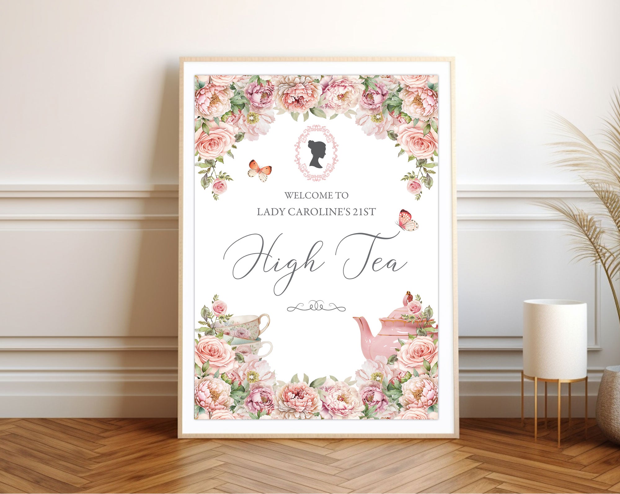 Pretty framed high tea invitation with floral design leaning on a wall.