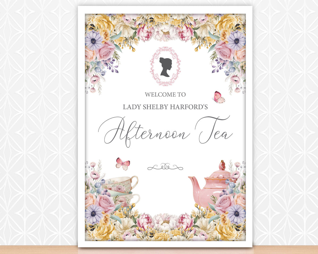 an A2 welcome sign for an afternoon tea event with floral decorations and a teapot in a white frame leaning up against some white patterned wallpaper