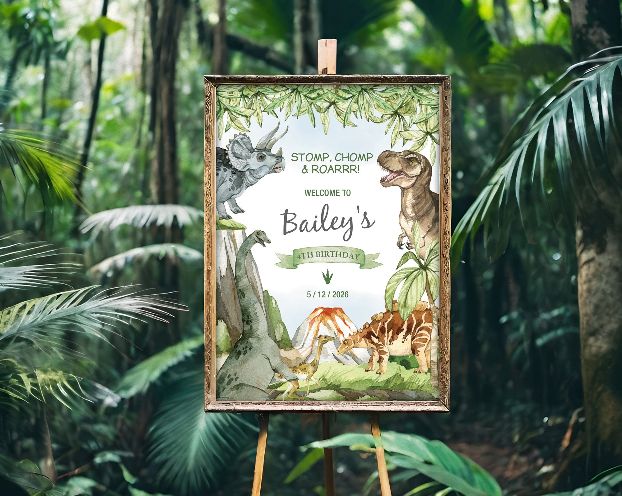A2 dinosaur jurassic party sign in a gold frame on an easel with a green lush forest in the background.