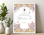 pastel welcome sign for an afternoon tea event with floral and teapot designs, in a frame, leaning up against a wall next to plants.