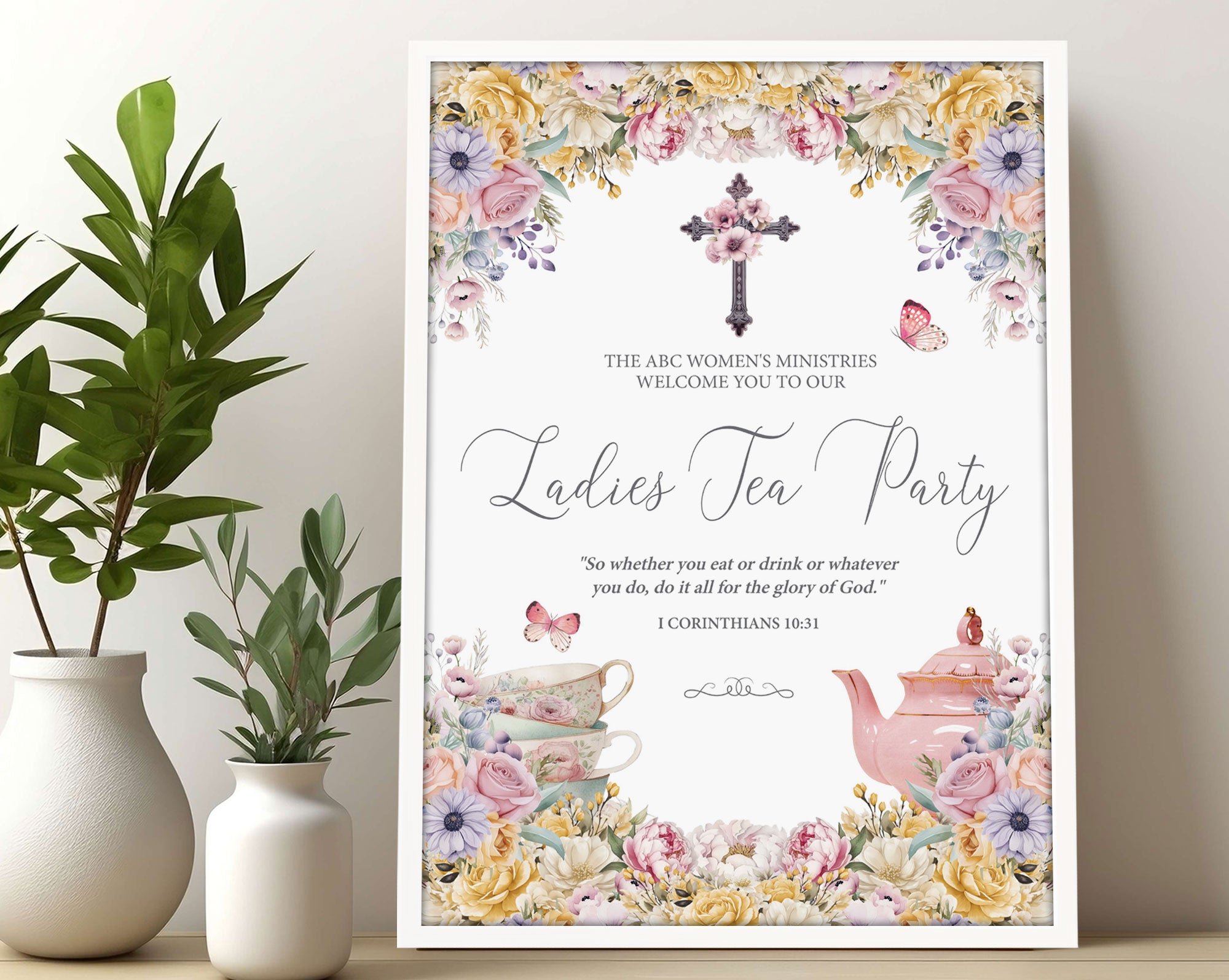 A3 Church Ladies Tea Welcome Sign in a white frame with Pastel flowers, Christian Cross and Teapot leaning up against a wall next to some greenery in vases