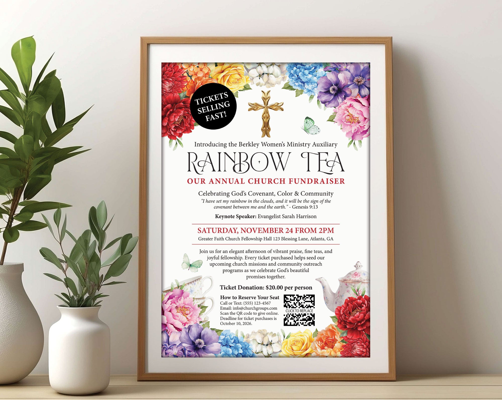 An A3 church rainbow tea advertising poster with gold cross, teapot and scripture in a wooden frame leaning up against a beige wall next to a vase with greenery