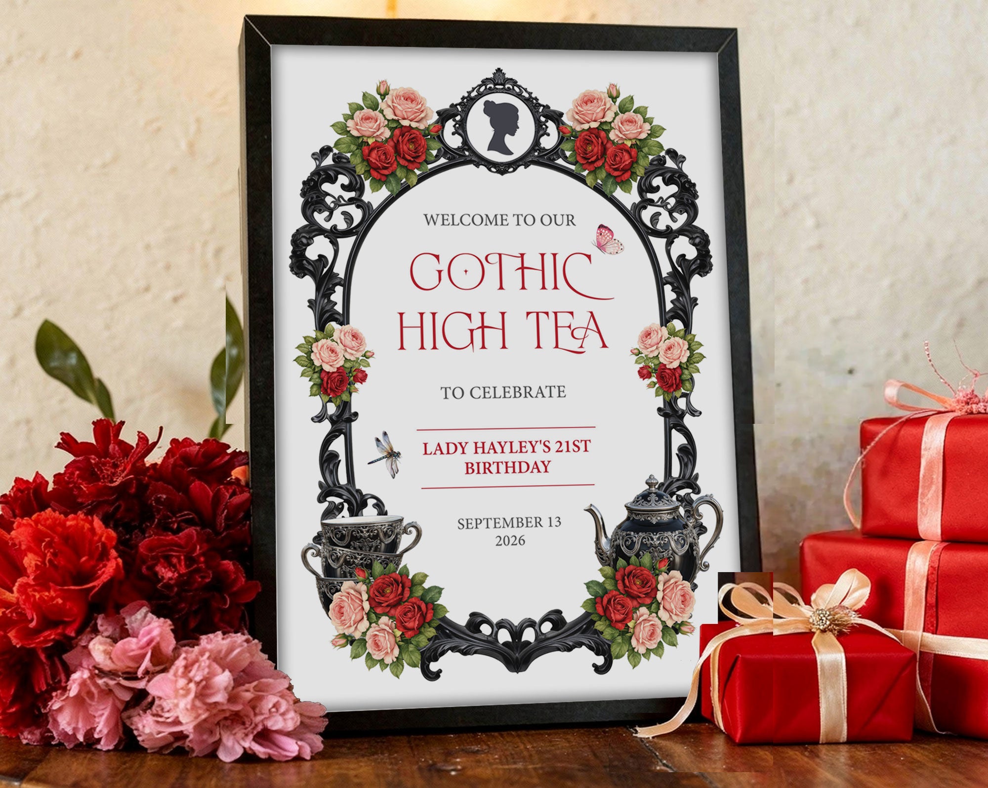 moody black and red A3 gothic high tea sign in a black frame on a wooden table surrounded by red and gold gifts and red and pink flowers