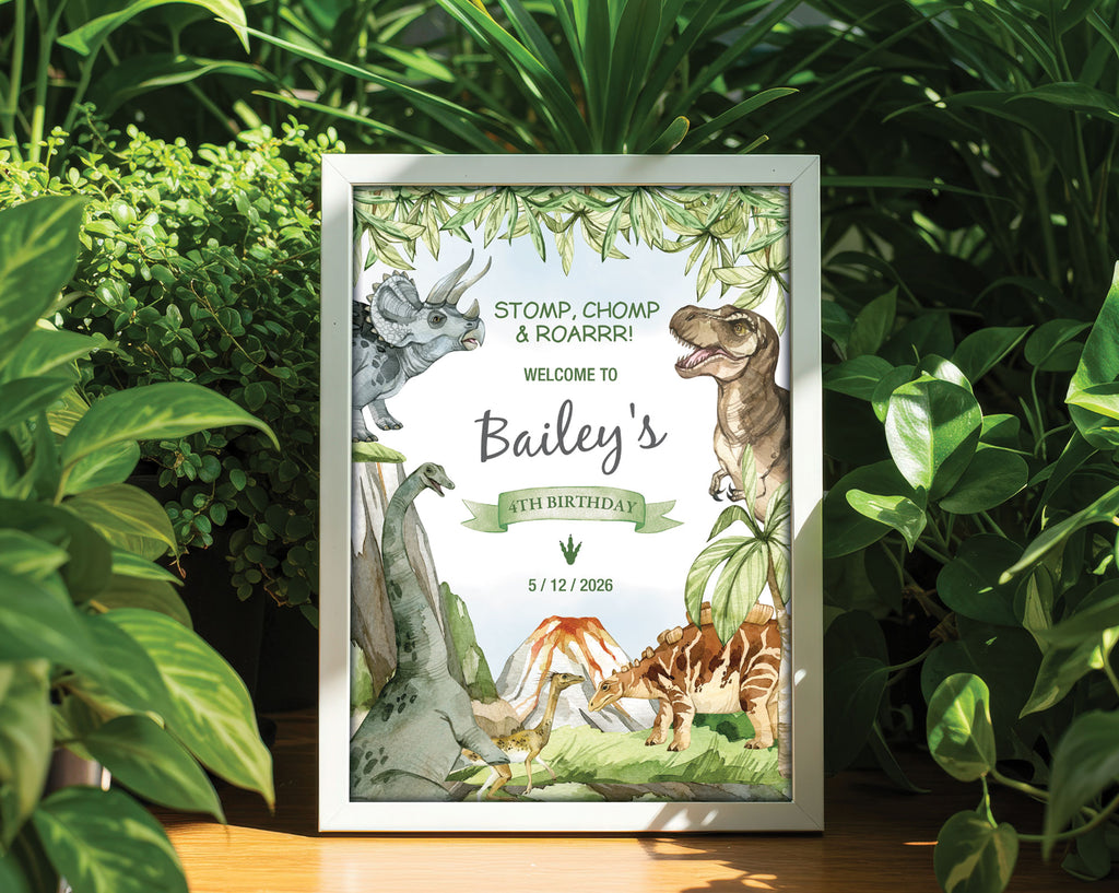 an A4 dinosaur welcome sign in a white frame on a table, surrounded by lush greenery.