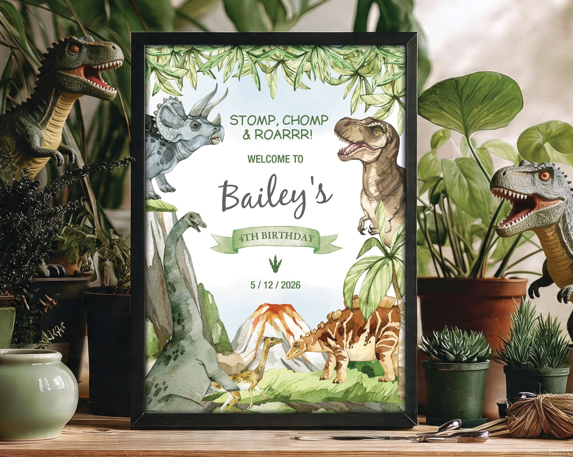 a dinosaur boy's party welcome sign in a black frame standing amongst greenery in pots with 2 toy dinosaurs in the background