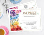 Two A4 printed certificates for 1st Prize Rainbow Tea Table Decoration, featuring a colorful floral border and decorative text, styled on a white tabletop with a teacup, saucer, cross, and plates in the background.