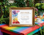 An A4, 2nd Prize Rainbow Tea certificate with colorful floral artwork in an ornate gold frame, displayed on a rainbow-colored table in an outdoor garden setting with plants and tea-time props.
