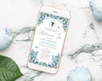 Phone displaying an afternoon tea invitation on a marble gold rimmed mobile with a dusty blue afternoon tea invitation displaying on it surface with decorative flowers and a leaf.