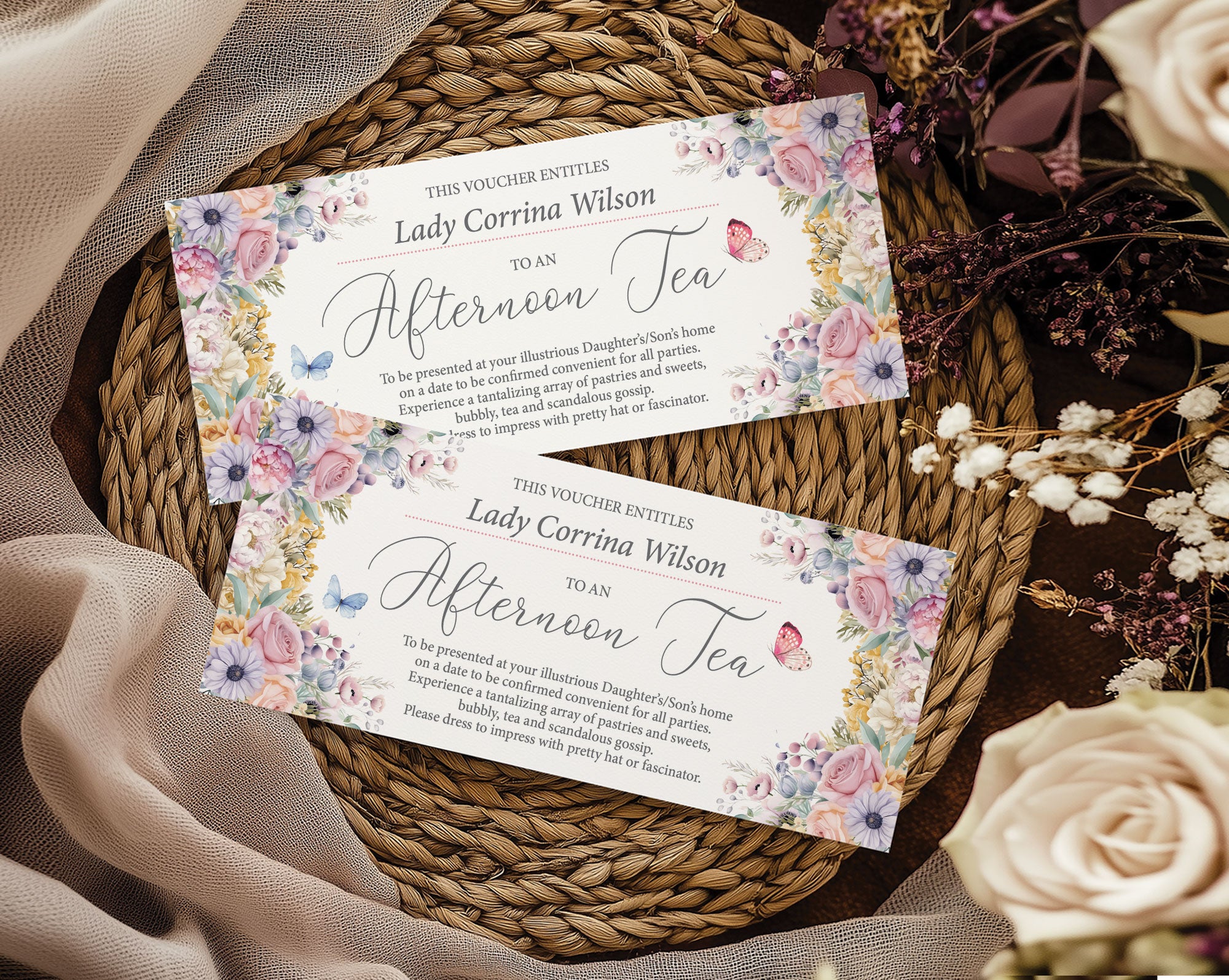 Two pastel flower and butterfly afternoon tea vouchers on a woven mat with flowers.