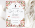 regency baby shower invitation with cameo, teapot and blush pink flowers laying on a white cloth with a knitted baby pacifier next to it