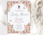 regency baby shower invitation with cameo, teapot and blush pink flowers laying on a white cloth with a knitted baby pacifier next to it