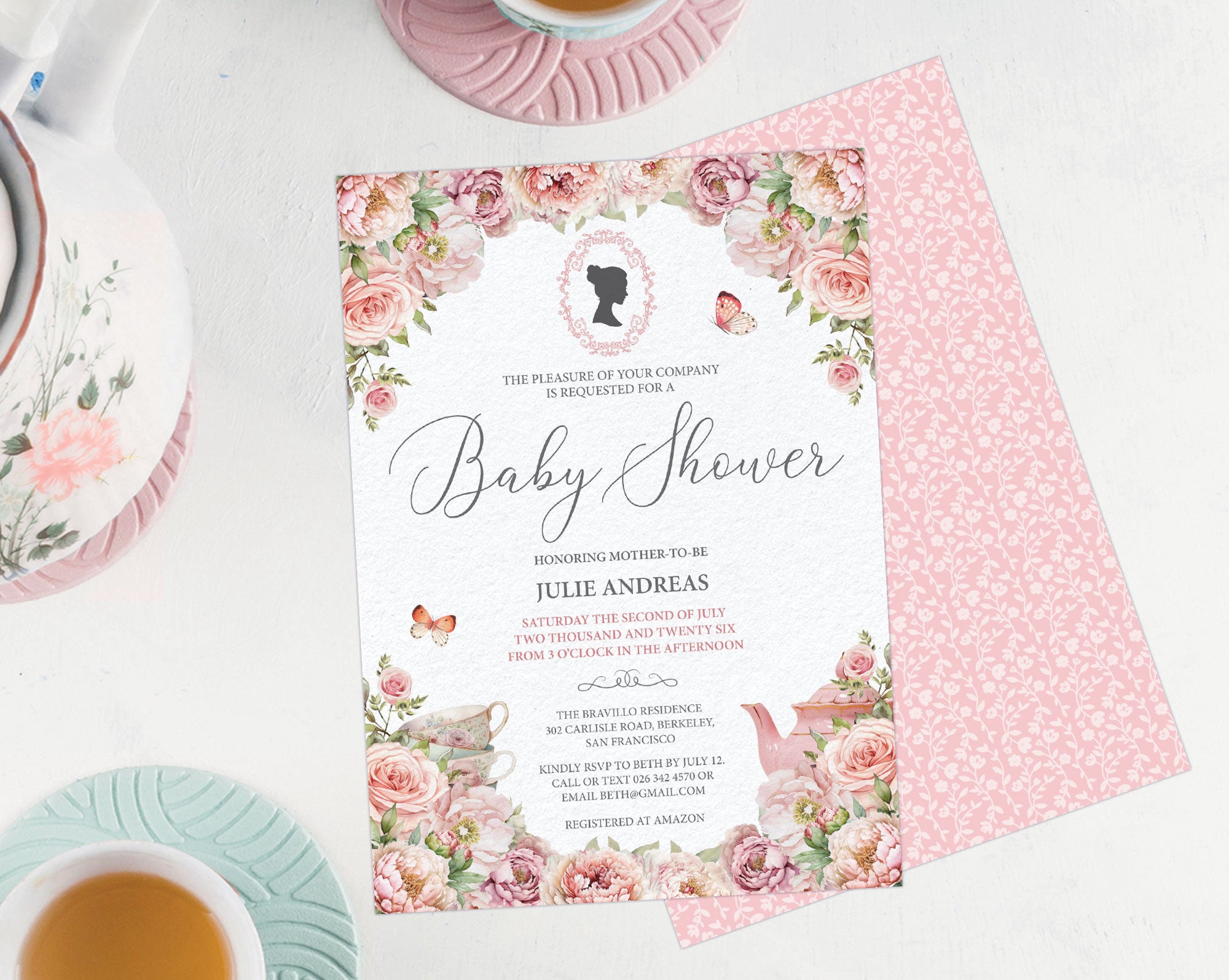 a blush pink flower baby shower invitation showing the front and the pink pattern back, laying on a white background next to a pastel tea service