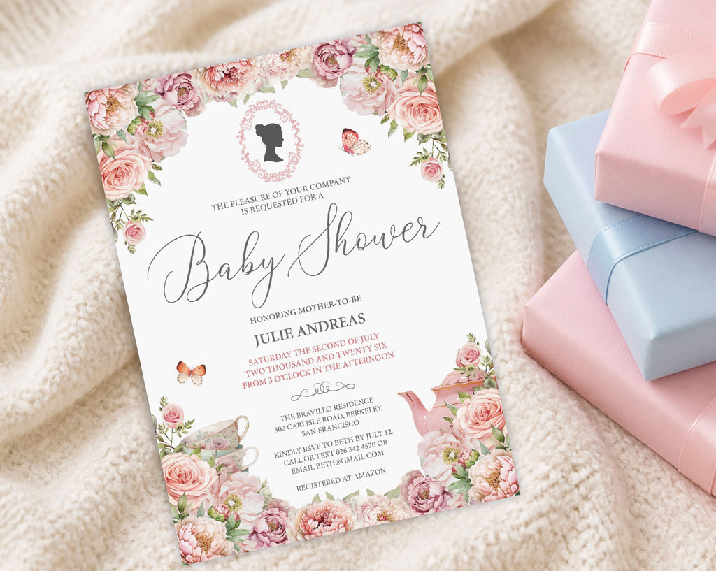 a blush pink baby shower invitation with cameo and flowers on a cream baby blanket next to some pink and blue wrapped gifts