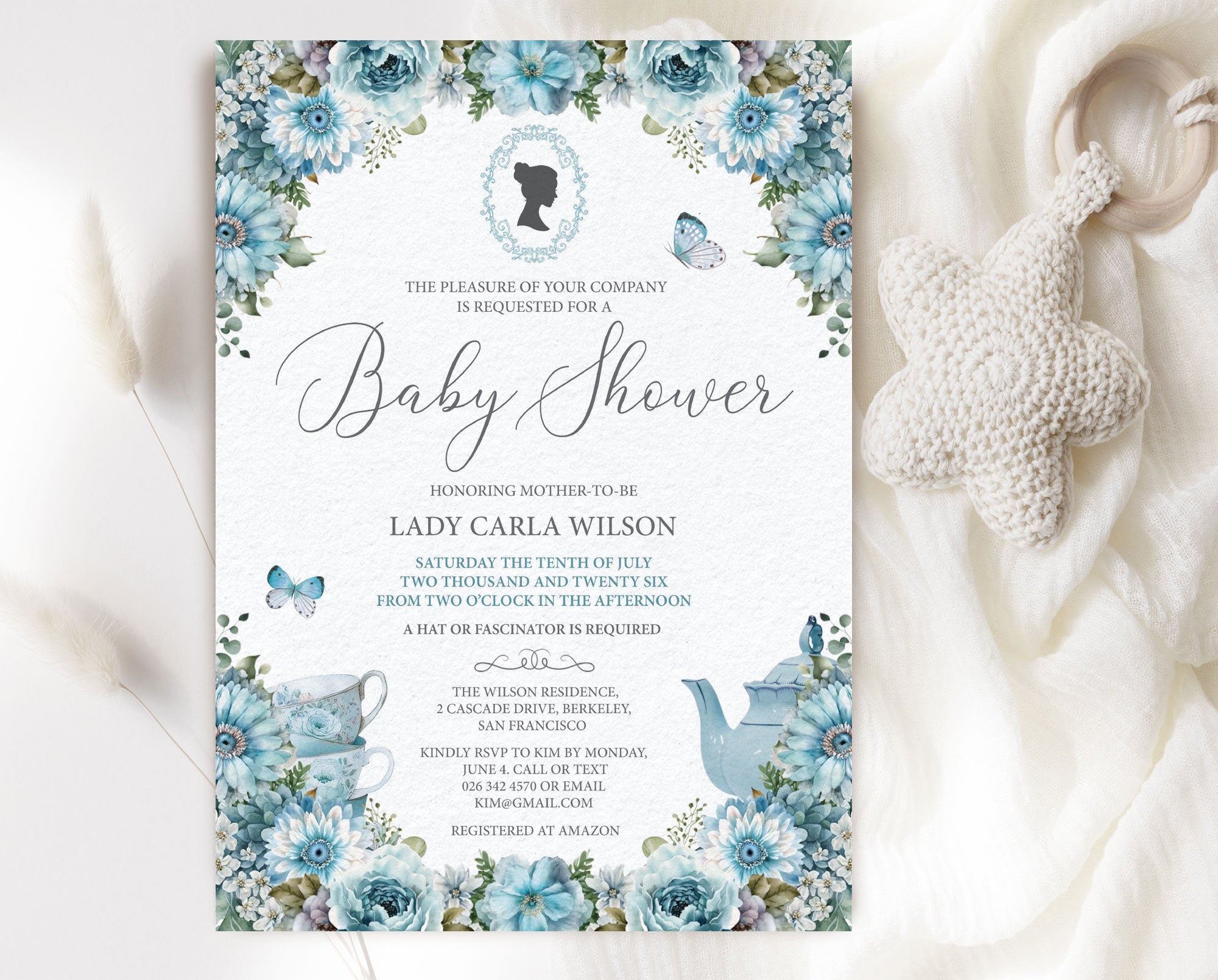 Regency Baby Shower Invitation Template with Dusty blue flowers and cameo graphic, laying on a white blanket with a baby pacifier