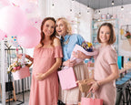 Three women, one is pregnant, posing together with balloons and gift bags in a tea store.