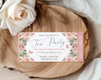 Pretty pink Tea party ticket with floral design on a wooden surface with white roses.