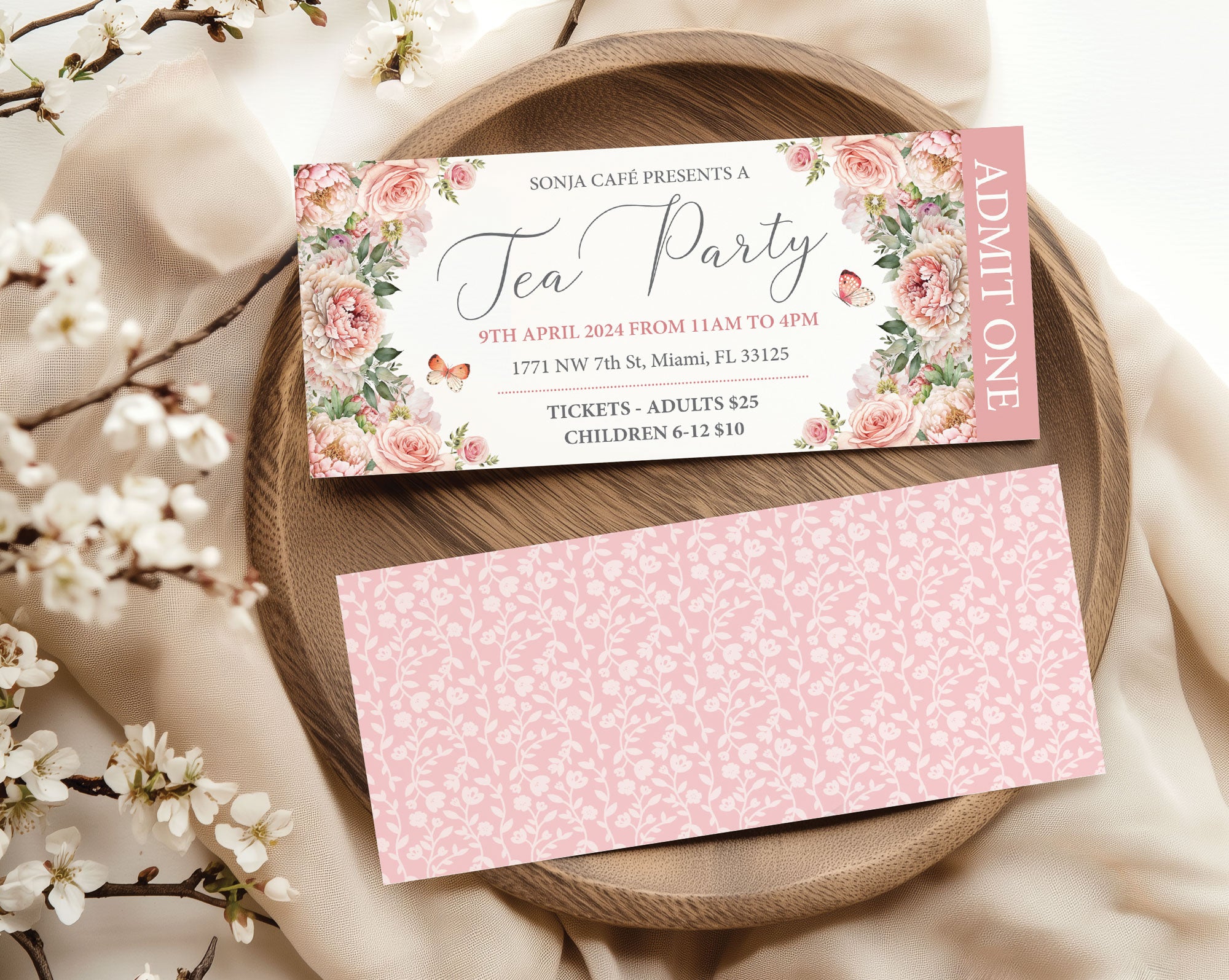 Blush pink Tea party event ticket with floral design on a wooden plate with cherry blossoms.