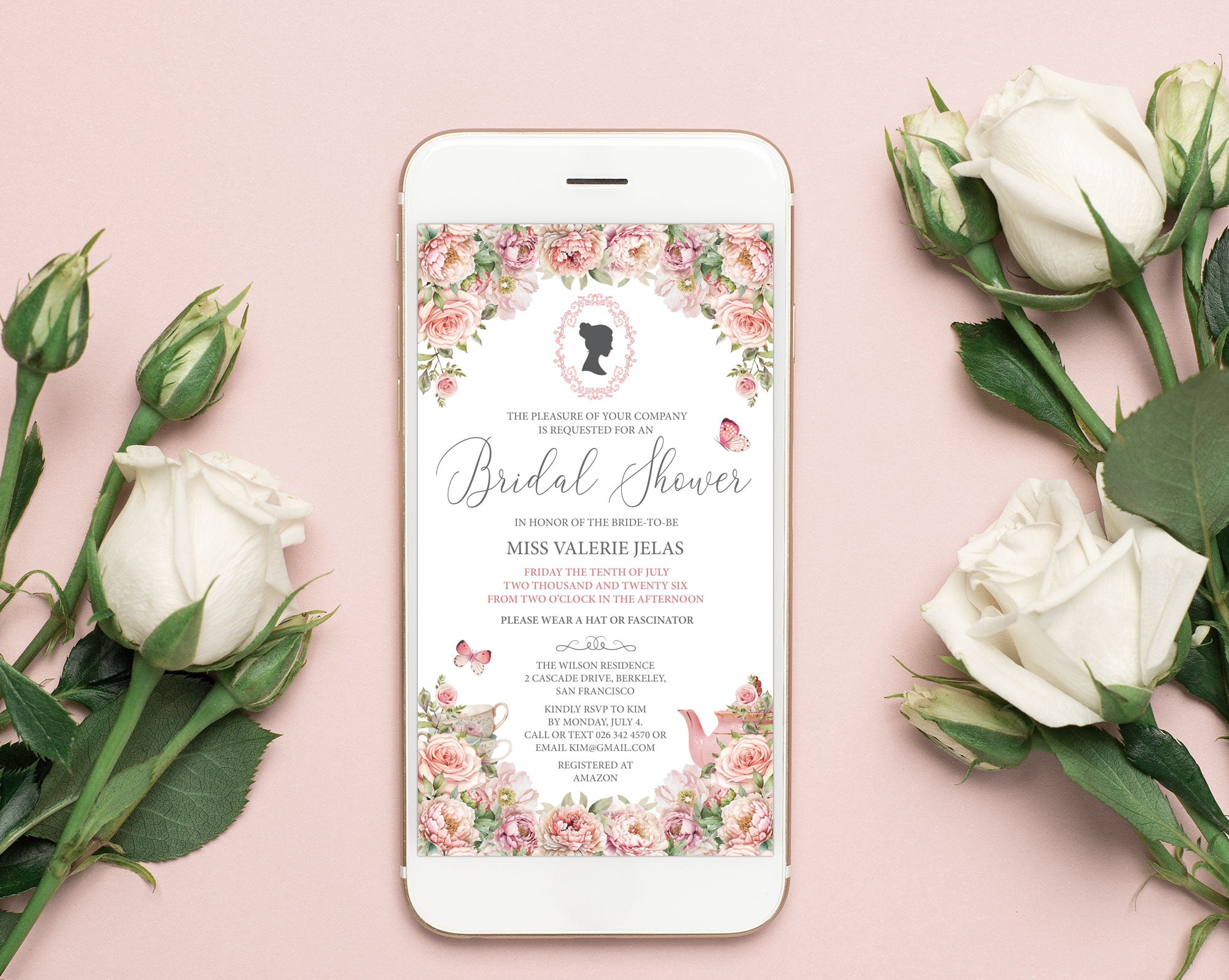 a pretty blush pink flower invitation showing on the screen of a white mobile phone laying on a pink background with white roses next to it