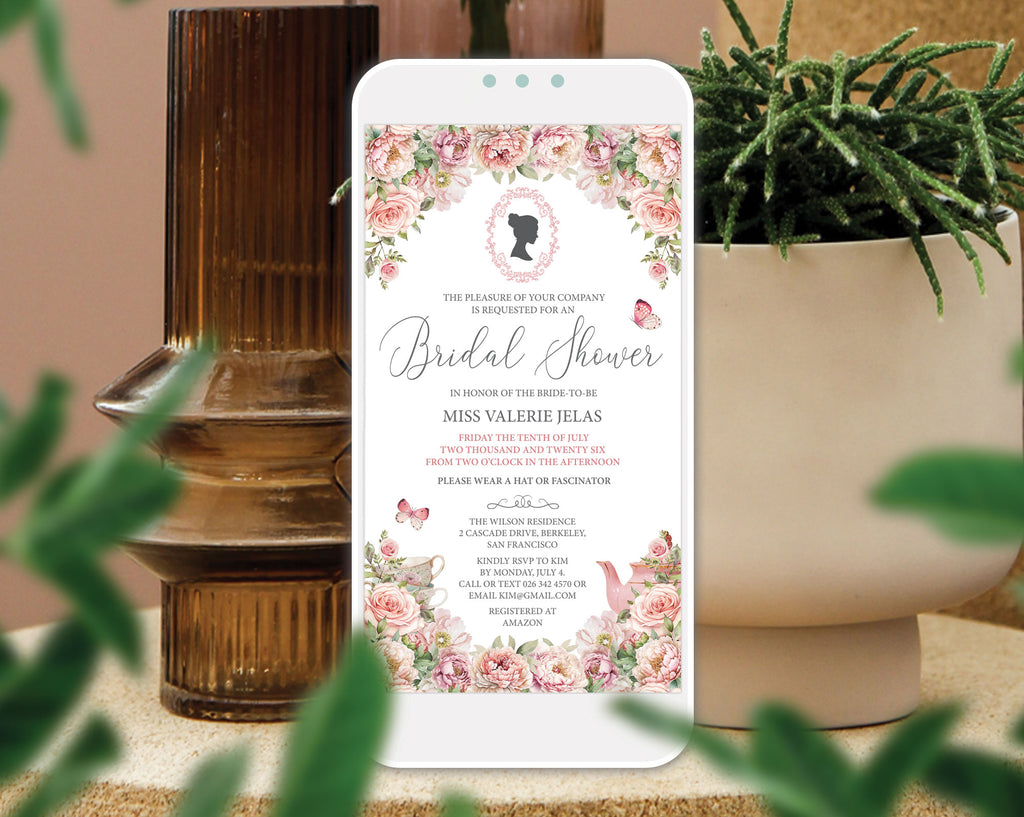 A mobile phone showing a Regency Bridal Tea blush pink Invitation with teapot and teacups, cameo and butterflies, leaning up against a vase with greenery