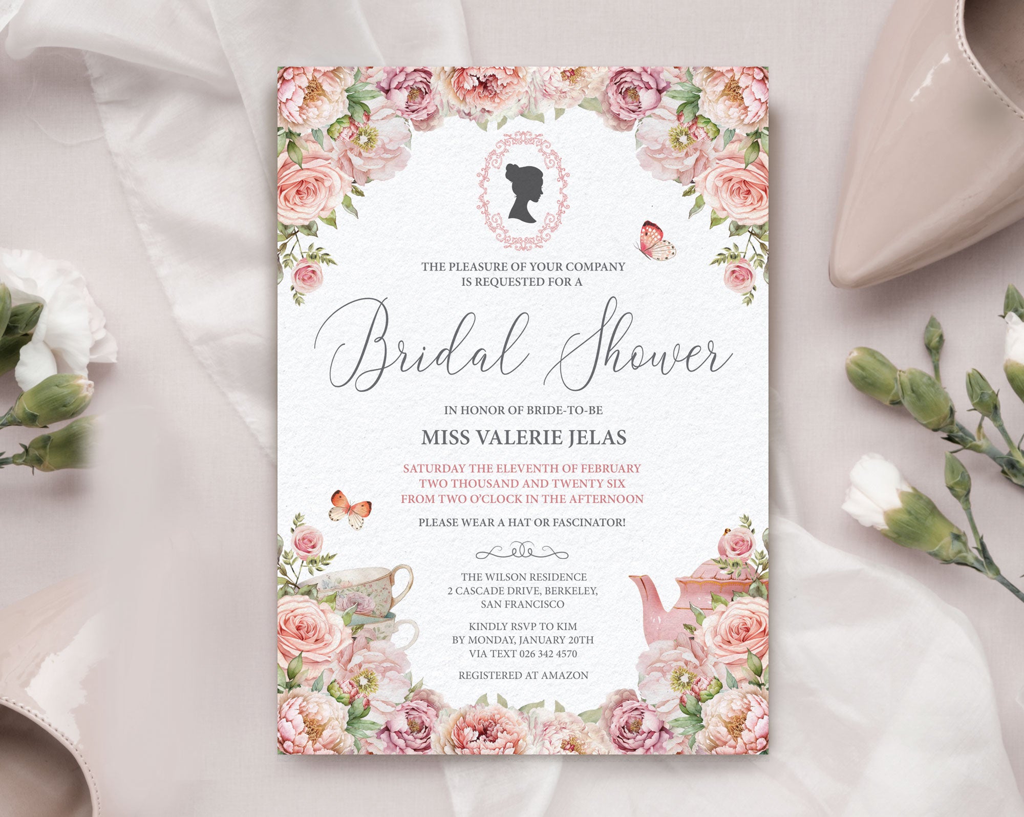 Bridal shower invitation with floral design on a white surface next to white carnations and a beige court shoe