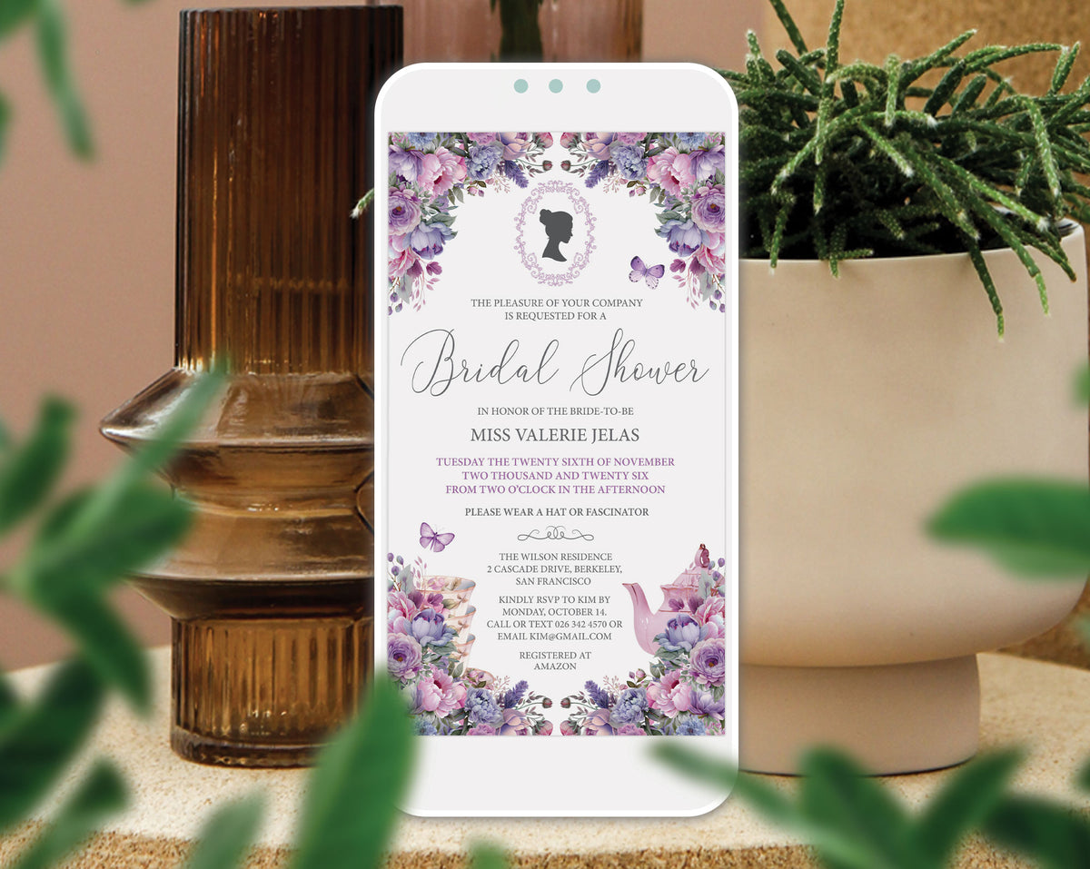 A smartphone centered in a styled setting, displaying a bridal shower invitation with purple floral borders and elegant script text. The phone is framed by a brown glass vessel on the left, a potted green plant on the right, and soft blurred foliage in the foreground.