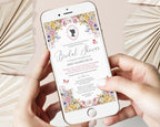 two hands holding a mobile phone with a pastel flower regency style bridal shower invitation showing on the screen, beige dried leaves in the background