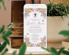 A mobile phone showing a pastel flower Regency Bridal Tea Invitation with teapot and teacups, cameo and butterflies on the screen, leaning up against a brown vase next to some greenery in a white pot