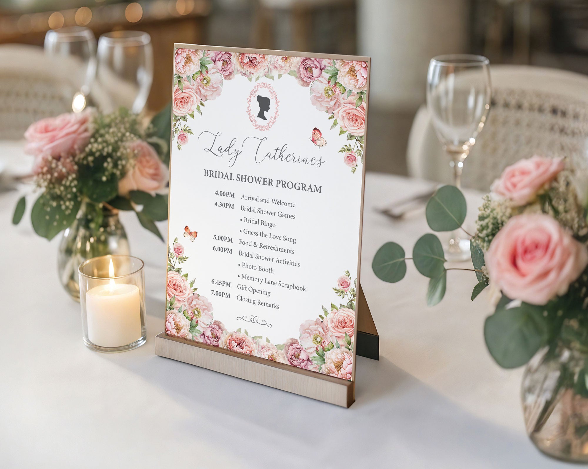 Bridal shower program sign with blush pink floral design on a table with flowers and candles.